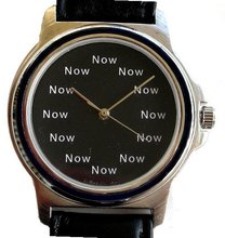 "Now" Is the Time That Is Shown Each Hour on the Black Dial of the Brushed Chrome Round with a Black Enamel Bezel and Black Leather Strap