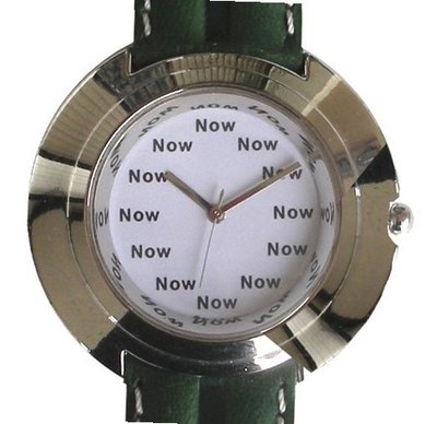 "Now" Is the Time That Is Shown Each Hour on the White Dial of the Jumbo Size Polished Chrome Round with a Green Leather Strap with White Stitching